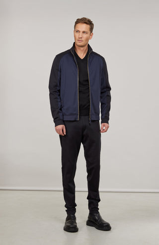 Sportliche Herrenjacke aus exklusivem Natural Powerstretch mit gerader, körperbetonter Passform und leicht verlängerter Silhouette. Ausgestattet mit modernem Stehkragen, markantem Zwei-Wege-Zipper und seitlichen Taschen mit verstecktem Reißverschluss. Das weiche, elastische und atmungsaktive Material mit seidig schimmernder Oberfläche sorgt für hohen Tragekomfort und maximale Bewegungsfreiheit. Eine hautfreundliche Baumwollschicht auf der Innenseite macht die multifunktionale Jacke besonders angenehm zu tra
