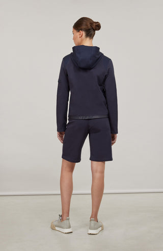Moderne Damen-Jacke mit Kapuze aus hochwertigem Materialmix aus Baumwolle, Leinen und Elasthan. Die Jacke kombiniert atmungsaktive Baumwollpartien an Vorder- und Rückenteil mit elastischen Natural-Powerstretch-Einsätzen an Kapuze, Ärmeln und Rumpfinnenseite für hohen Tragekomfort und optimale Bewegungsfreiheit. Ausgestattet mit zwei Eingrifftaschen mit Zipp, beidseitig zu öffnendem Frontreißverschluss und edlen, waschbaren Alcantara-Lederdetails. Vielseitig kombinierbar für sportliche, urbane oder casual Lo