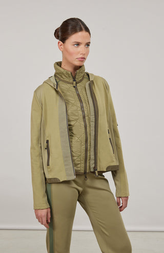 Moderne Damen-Jacke mit Kapuze aus hochwertigem Materialmix aus Baumwolle, Leinen und Elasthan. Die Jacke kombiniert atmungsaktive Baumwollpartien an Vorder- und Rückenteil mit elastischen Natural-Powerstretch-Einsätzen an Kapuze, Ärmeln und Rumpfinnenseite für hohen Tragekomfort und optimale Bewegungsfreiheit. Ausgestattet mit zwei Eingrifftaschen mit Zipp, beidseitig zu öffnendem Frontreißverschluss und edlen, waschbaren Alcantara-Lederdetails. Vielseitig kombinierbar für sportliche, urbane oder casual Lo