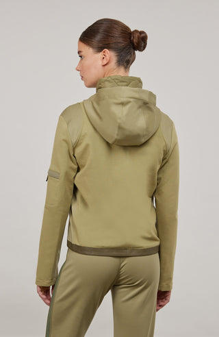 Moderne Damen-Jacke mit Kapuze aus hochwertigem Materialmix aus Baumwolle, Leinen und Elasthan. Die Jacke kombiniert atmungsaktive Baumwollpartien an Vorder- und Rückenteil mit elastischen Natural-Powerstretch-Einsätzen an Kapuze, Ärmeln und Rumpfinnenseite für hohen Tragekomfort und optimale Bewegungsfreiheit. Ausgestattet mit zwei Eingrifftaschen mit Zipp, beidseitig zu öffnendem Frontreißverschluss und edlen, waschbaren Alcantara-Lederdetails. Vielseitig kombinierbar für sportliche, urbane oder casual Lo