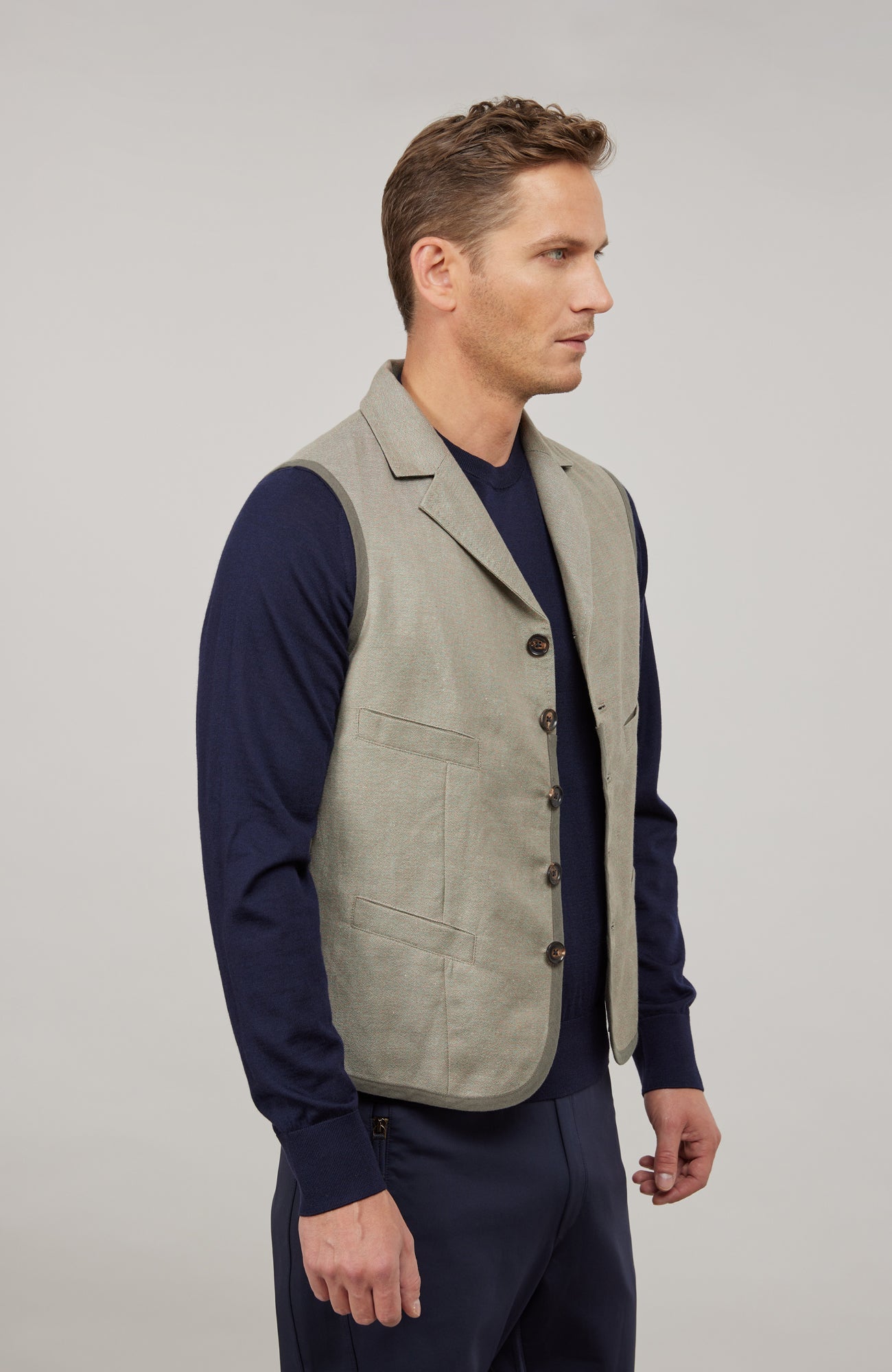 Ärmelloses Herren-Gilet aus hochwertigem Baumwoll-Leinen-Mix mit angenehm weichem Griff und dezenter melierter Optik. Moderner, neu interpretierter Schnitt mit maskuliner Silhouette und markantem Reverskragen. Mit Knopfleiste, aufgesetzten Brust- und Fronttaschen sowie kleiner Eingrifftasche links. Abgerundeter Saum für dynamische Linien und eingefasste Baumwollbänder an Saum, Taschen und Seitennähten als dezente Details. Vielseitig kombinierbar und als maskulines Fashion-Statement geeignet.