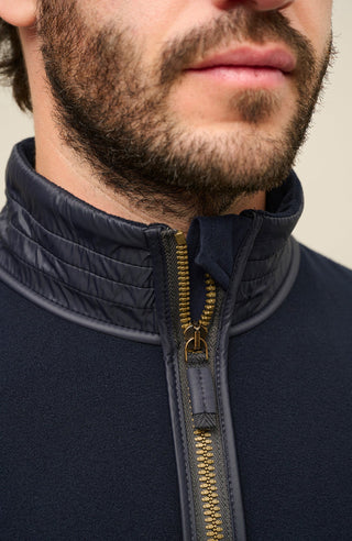Detailansicht der Herrenjacke „Oliver BF 163-0“ von Frauenschuh in der Farbe „Midnight“, einem tiefen Dunkelblau. Die Nahaufnahme zeigt präzise Verarbeitungsdetails, einen Reißverschluss und den Kragen. Das hochwertige Material wirkt glatt, leicht strukturiert und funktional. Die Aufnahme betont die exzellente Handwerkskunst, die klare Linienführung und das minimalistische Design der Jacke – ideal für anspruchsvolle Träger