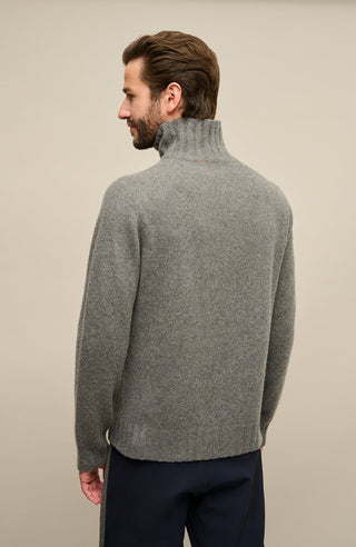 Rückansicht-Bild eines Herrenpullovers aus 100 % Kaschmir von Frauenschuh, Modell „Aiden 2.0“ (Artikelnummer WS_131-0) in der Farbe Grau. Der edle Cashmere-Strickpullover wird von einem männlichen Model getragen und zeigt auf der Rückseite eine klare, puristische Linienführung mit fein gestricktem Rumpf und kontrastierenden Rippenbündchen an Ärmelenden und Saum. Der schmale Stehkragen schmiegt sich elegant an den Nacken an und unterstreicht das sportlich-elegante Design.