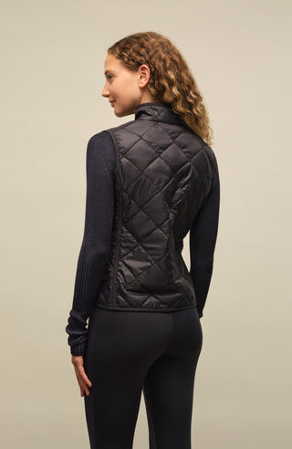 Sportliche Reiterweste Nora Quilt aus leichtem Quilt Light mit 40 g Hochdaunen-Vlies für angenehme Wärme bei minimalem Gewicht. Atmungsaktiv sowie wasser- und schmutzabweisend. Kleiner Stehkragen, mit Leinen eingefasste Nähte und hochwertige Metalldruckknöpfe prägen den klaren Look. Seitliche Taschen mit nahtfeinem Reißverschluss sorgen für Funktionalität. Das fein gesteppte italienische Nylon im klassischen Rautenmuster verleiht der Weste eine elegante, sportive Optik. Leicht verstaubar und ideal für unter