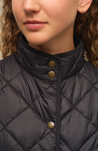 Sportliche Reiterweste Nora Quilt aus leichtem Quilt Light mit 40 g Hochdaunen-Vlies für angenehme Wärme bei minimalem Gewicht. Atmungsaktiv sowie wasser- und schmutzabweisend. Kleiner Stehkragen, mit Leinen eingefasste Nähte und hochwertige Metalldruckknöpfe prägen den klaren Look. Seitliche Taschen mit nahtfeinem Reißverschluss sorgen für Funktionalität. Das fein gesteppte italienische Nylon im klassischen Rautenmuster verleiht der Weste eine elegante, sportive Optik. Leicht verstaubar und ideal für unter