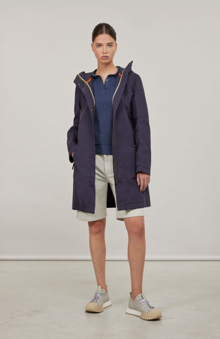 Damen-Knielanger Mantel aus Outdoor Cotton, wasser- und windabweisend, gerade Passform mit schmaler Silhouette, Stehkragen und weitenregulierbare Kapuze, Knopfleiste mit verdecktem Zwei-Wege-Zipper, Ripsband an Ärmelabschlüssen und Saum, seitliche Taschen mit markantem Zipper. In der Farbe Dunkelblau (Farbe: midnight).