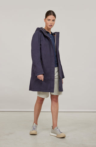 Knielanger Damenmantel in Midnight Dorothee aus Outdoor Cotton aus Baumwolle. Wasser- und windabweisend durch spezielle Webtechnik. Gerade Passform mit schmaler Silhouette, Stehkragen und weitenregulierbarer Kapuze. Verdeckter Zwei-Wege-Zipper mit Knopfleiste, seitliche Taschen mit Zipper sowie Ripsband-Details an Ärmelabschlüssen und Saum. Sportlich-elegant und funktional.
