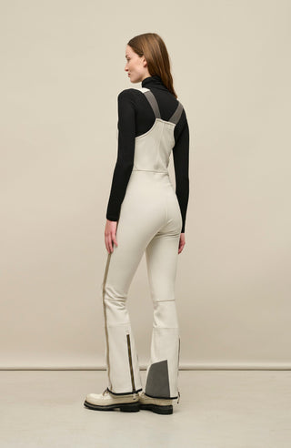 Ski-Catsuit Davina2.0-S im Latzhosen-Stil ohne Ärmel, schmaler figurbetonter Schnitt mit ausgestelltem Bein, femininer Bustier-Ausschnitt, Streifen an den Beinaußenseiten aus Alcantara-Leder, Träger hinten aus elastischem Gummi, ergonomisches Knie, markanter langer Zipper, auffallende Nähte, Seitentaschen mit Zip, Kantenschutz aus Alcantara-Leder und Schneefang. Enganliegend, feminin, betont Silhouette und Bewegungsfreiheit. In der Farbe Weiß-Beige (Farbe: sandstone)