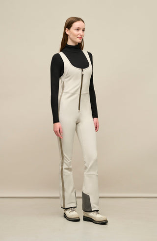 Ski-Catsuit Davina2.0-S im Latzhosen-Stil ohne Ärmel, schmaler figurbetonter Schnitt mit ausgestelltem Bein, femininer Bustier-Ausschnitt, Streifen an den Beinaußenseiten aus Alcantara-Leder, Träger hinten aus elastischem Gummi, ergonomisches Knie, markanter langer Zipper, auffallende Nähte, Seitentaschen mit Zip, Kantenschutz aus Alcantara-Leder und Schneefang. Enganliegend, feminin, betont Silhouette und Bewegungsfreiheit. In der Farbe Weiß-Beige (Farbe: sandstone)